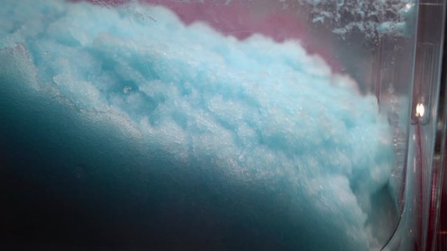 Ice cold sorbet machine mixing fruit juice. Freezing slush spinning around, summer treat. Crushed iced coloured with fruit flavor sweeteners