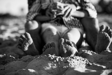 young couple lying on the sand, focus on the feet