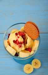 ice cream dessert with banana pieces and frozen raspberries and chocolate cake on a blue background