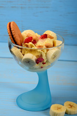 ice cream dessert with banana pieces and frozen raspberries and chocolate cake sprinkled with nuts