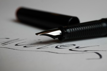 Contract conclusion concept: Macro close up of isolated black ink pen and handwritten signature on...