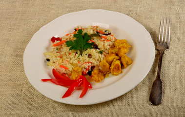 pieces of fried chicken in curry with rice and vegetables on a white plate