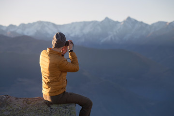 A tourist photographs the mountainous landscape. Travel into the countryside.
