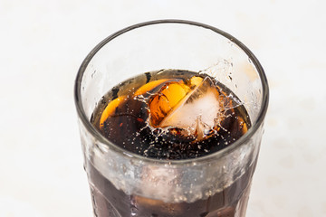 whiskey cocktail with cola and ice in a transparent glass with beautiful splashes