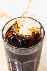 whiskey cocktail with cola and ice in a transparent glass with beautiful splashes