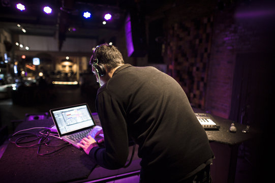 Rear View Of Man Using Laptop While Standing In Nightclub