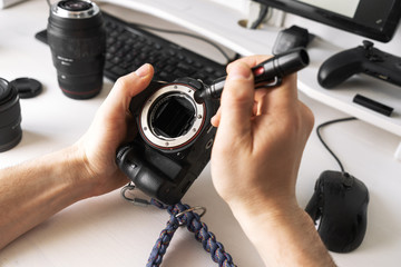 A man cleans the matrix of the camera from dust with a special pencil.