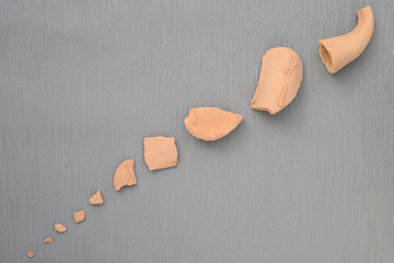 shattered red pottery clay on grey backround. Close up. No people. Top view. Flat lay. Copy space.