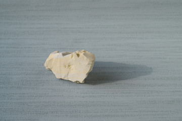 Shattered white clay on the cyan background. Close up. Ural food clay. No people..There is noise...