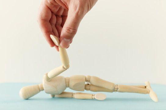 concept image of helping hand and support. male hend helping wooden dummy. metaphor of trouble and stress