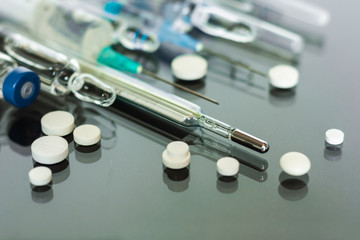 Thermometer, pills, injection vaccine ampoules, syringeon glass background, Coronavirus, MERS-CoV,...