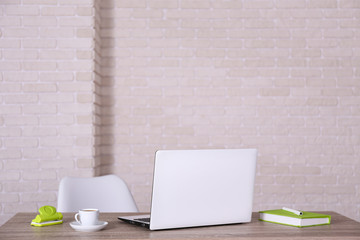 Creative workspace of a blogger. White laptop computer on wooden table in loft style office with brick walls. Designer's table concept. Close up, copy space, background.
