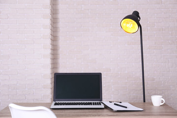 Creative workspace of a blogger. White laptop computer on wooden table in loft style office with brick walls. Designer's table concept. Close up, copy space, background.