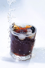 whiskey cocktail with cola and ice in a transparent glass with beautiful splashes