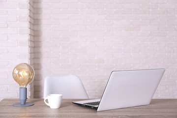 Creative workspace of a blogger. White laptop computer on wooden table in loft style office with brick walls. Designer's table concept. Close up, copy space, background.