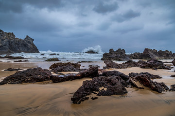 Fototapeta na wymiar Rocks at the beach of the Camel Rock bay in New South Wales, Australia at a cloudy and windy day in summer with strong waves in the ocean. 