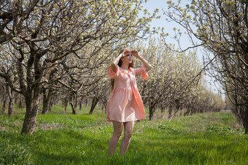 Obraz premium Beautiful blonde woman walks through a flowering garden