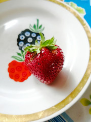 Bright red large strawberry with leaves.