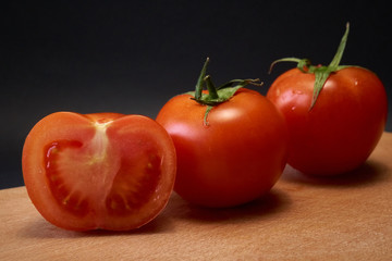 Red tomato, black board, black background.