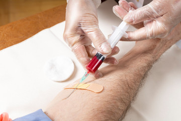 Hands of a nurse take blood from a male hand for analysis.
Taking venous blood from a patient. Side view. Closeup.