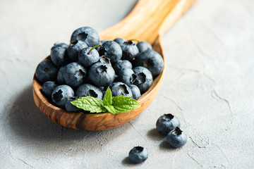 Fresh blueberries in  wooden spoon, macro, concrete background