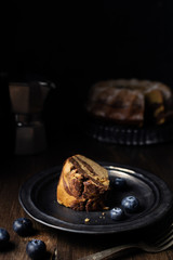 Piece of served chocolate and vanilla marble bundt cake with blueberries and coffee