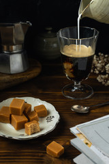 Fototapeta na wymiar Close-up of coffee glass with some salted caramel fudge dark wooden table