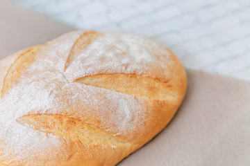 Beautiful white handmade bread on a linen towel on a light kitchen table. Healthy eating Close-up. Top view. Space for text.