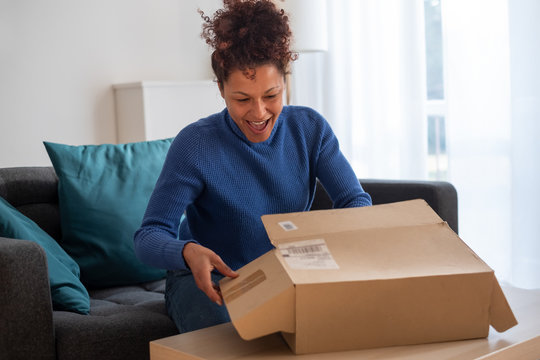 Happy black woman unboxing just delivered item after home shopping