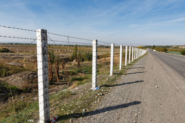 state border between Kyrgyzstan and Uzbekistan, road along a barbed wire fence.