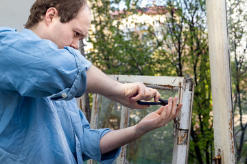 Man repairing old broken wooden windows using a pair of pliers. Repairing interior of old house. Close-up of home DIY