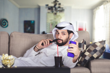 Arab young man lounge in a sofa playing with mobile. quarantine concept.
