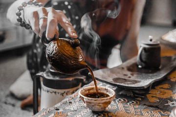 Chinese traditional tea ceremony. Tea is pouring from the teapot. A woman is making tea.