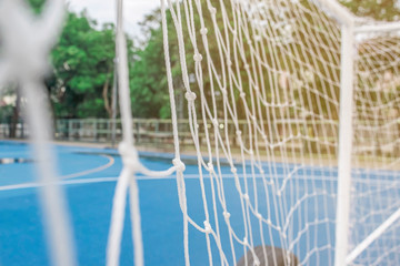 Soccer or football net background, view from behind the goal with blurred blue  field pitch