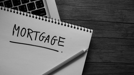 Mortgage words written in an office notebook on a wooden table. Financial & Business concept.