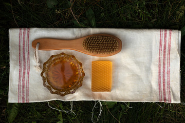 Honey soap lies on a light cotton towel. Nearby lies a body brush and natural honey. Set of accessories for sauna and steam room. The concept of returning to the roots of life and body care