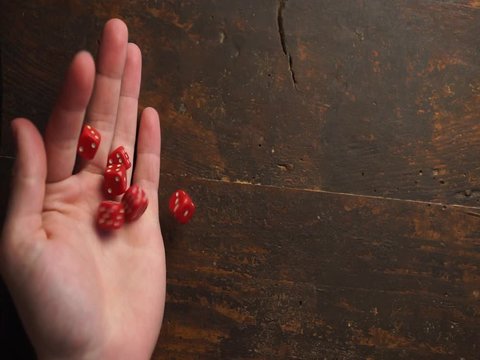 Rolling lot of red D6 dices on dark old brown wooden surface closeup roleplaying playing, wargaming tabletop