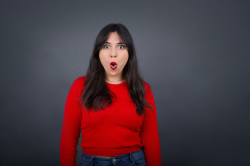 Headshot of goofy surprised bug-eyed young woman student wearing casual grey t-shirt staring at camera with shocked look, expressing astonishment and shock, screaming Omg or Wow