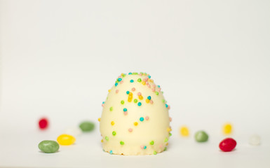 Fototapeta na wymiar Ei aus Schokolade mit bunten Zucker Streuseln isoliert vor weißem Hintergrund, Symbol Illustration Ostern