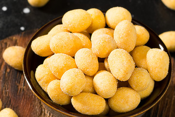 Grilled peanuts in cheese sauce in a brown bowl on a black table. Close up