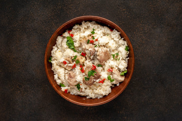 Homemade pilaf with meat and spices in a bowl on a stone table. Eastern cuisine.