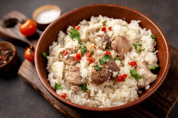 Homemade pilaf with meat and spices in a bowl on a stone table. Eastern cuisine.