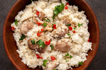 Homemade pilaf with meat and spices in a bowl on a stone table. Eastern cuisine.
