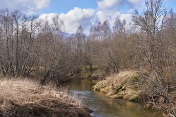 A winding river with steep banks, dry grass and trees