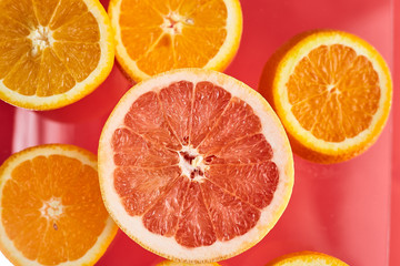 
Slices of fresh orange and grapefruit on red background top view. Citrus Juice Concept, Vitamin C, Fruits. Creative summer background