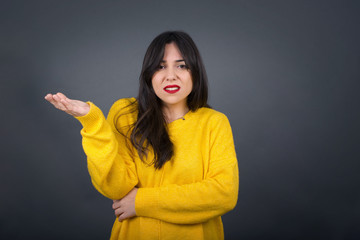 What the hell are you talking about, nonsense. Studio shot of frustrated female with blonde hair gesturing with raised palm, frowning, being displeased and confused with dumb question over gray wall.