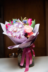 A large bouquet of flowers of various kinds stands in a transparent vase.