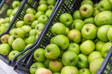 Baskets filled with green apples at a supermarket. Nutritious fruit. Side view.