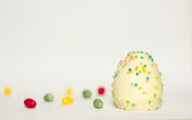 Fototapeta na wymiar Ei aus Schokolade mit bunten Zucker Streuseln isoliert vor weißem Hintergrund, Symbol Illustration Ostern