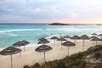 beautiful straw umbrellas on the beach on the empty beach, bright blue water and sky, paradise tropical beach,relaxing time,,amazing view,no people, sunset background. selective focus